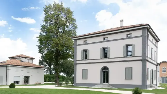 Zwei Gebäude mit mediterraner Bauweise und frisch sanierter Aussenfassade in weiss mit grauen Kontrastelementen