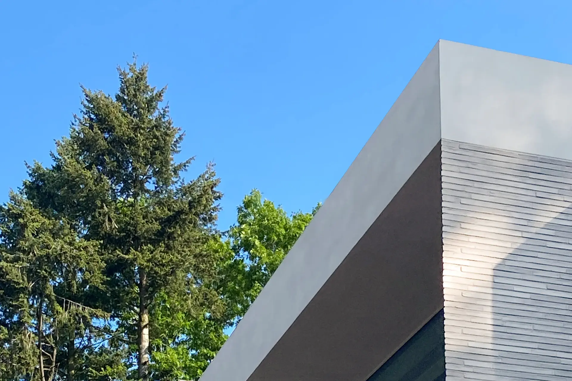 Reduzierter Dachabschluss an einem modernen Neubau, der die klare, kubische Formensprache des Gebäudes unterstreicht.