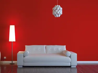 Der Wohnbereich mit einer roten Wand im Hintergrund des Sofas schafft einen lebendigen und einladenden Akzent