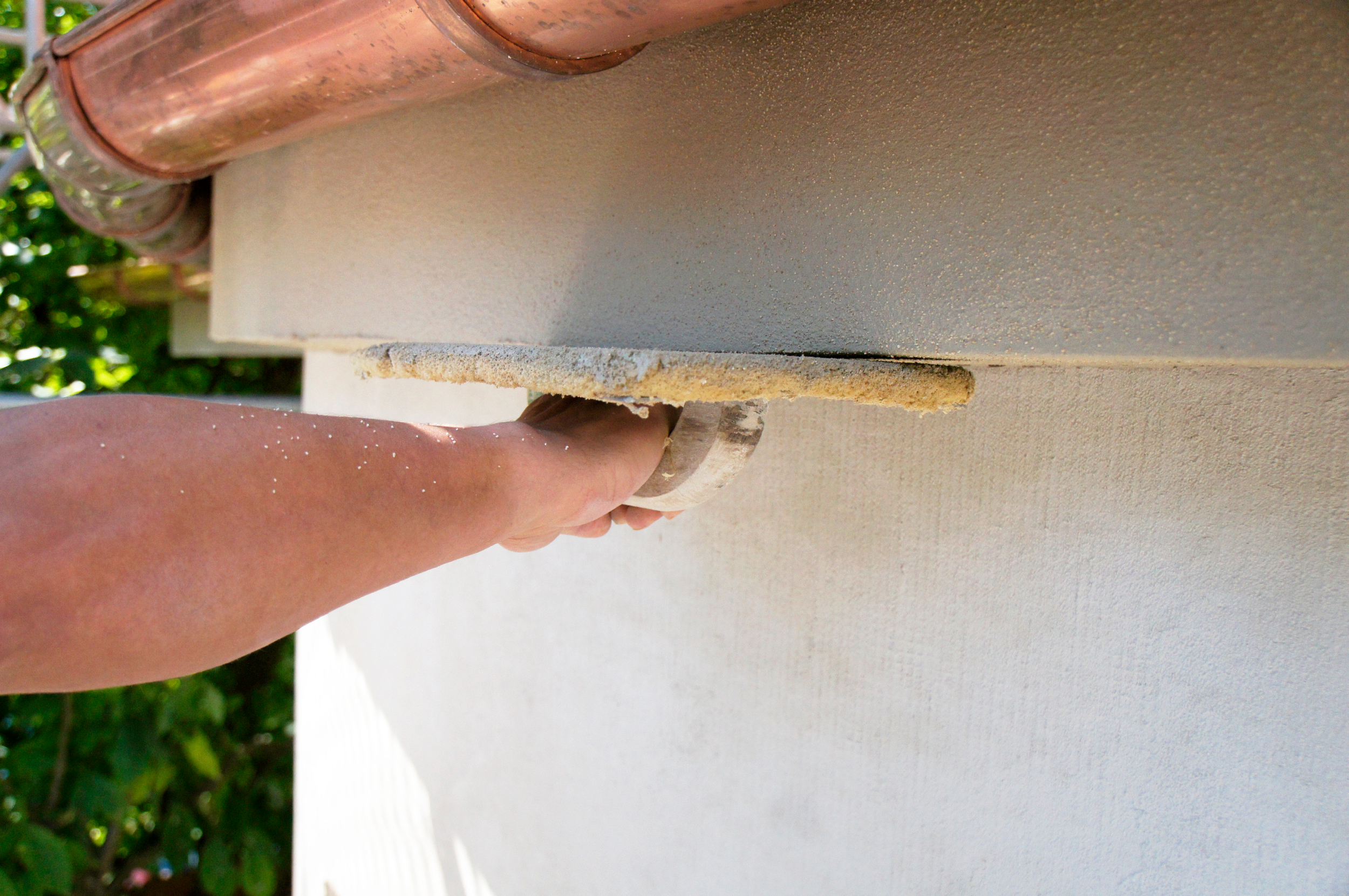 Hand mit Kelle streicht Wand eines Denkmals glatt