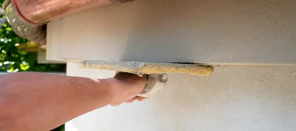 Hand mit Kelle streichen Wand glatt
