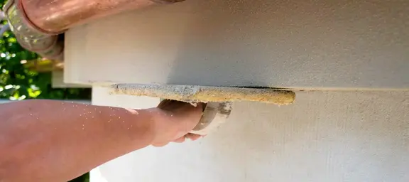 Hand mit Kelle streicht Wand eines Denkmals glatt