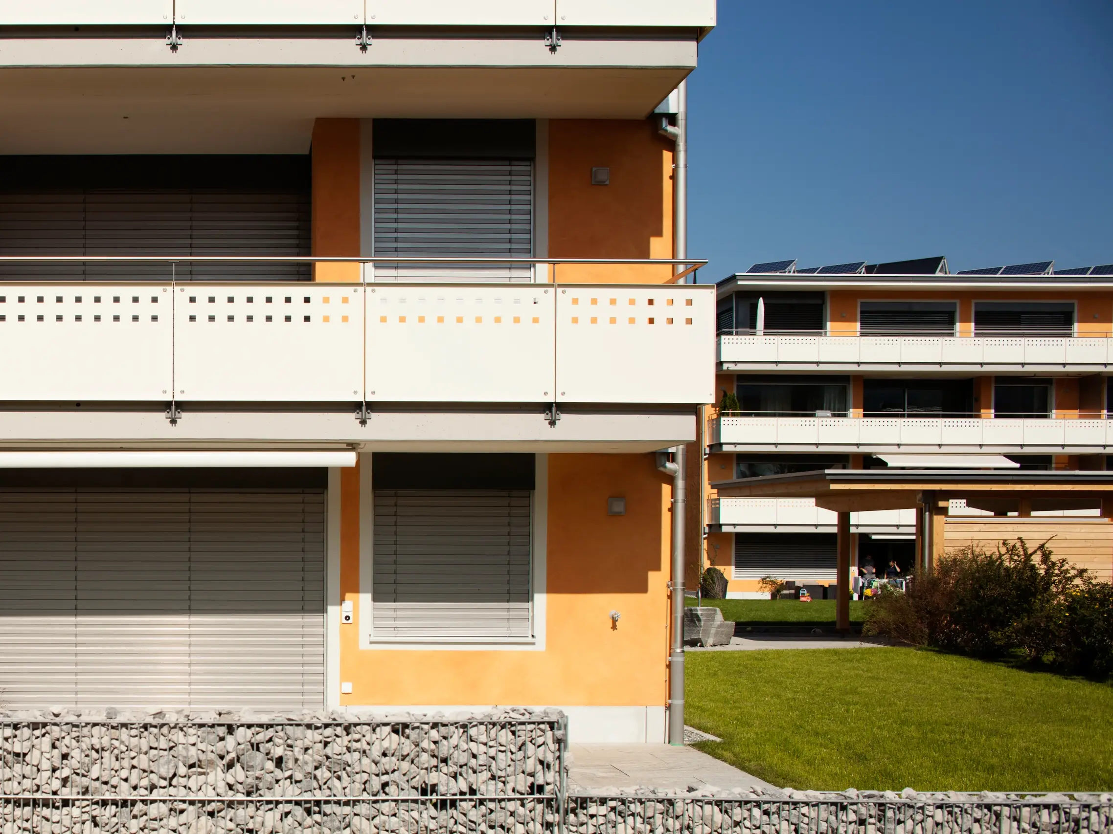 Detailansicht orange verputzte Gebäudekante mit Stahlbalkon und Schottersteinen
