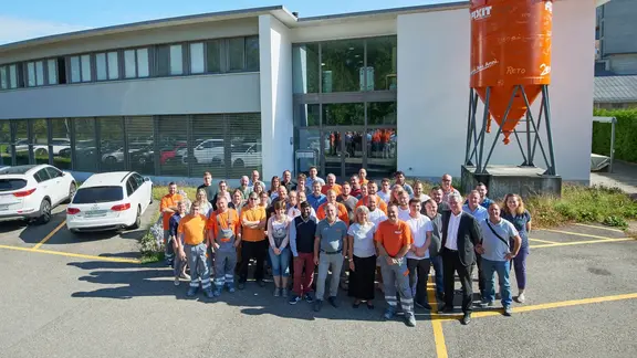 Fixit AG Photo de groupe de tous les collaborateurs du site de Holderbank AG devant le bâtiment administratif avec le silo Fixit