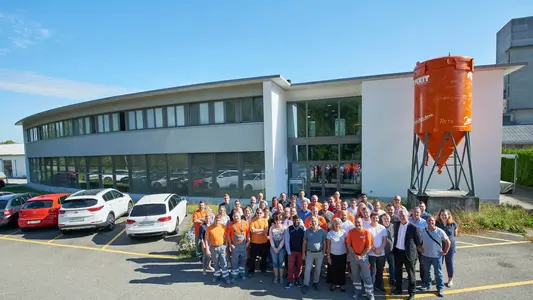 Fixit AG Photo de groupe de tous les collaborateurs du site de Holderbank AG devant le bâtiment administratif avec le silo Fixit