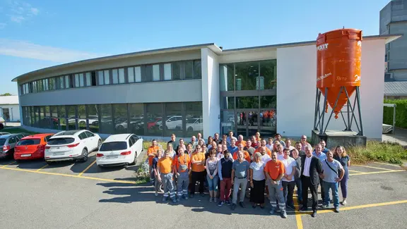 Fixit AG Gruppenfoto aller Mitarbeiter am Standort in Holderbank AG vor dem Verwaltungsgebäude mit Fixit Silo