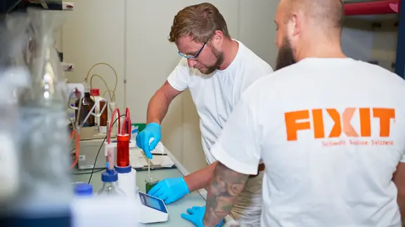 Deux collaborateurs de Fixit travaillent au laboratoire sur un récipient de mesure avec pipette