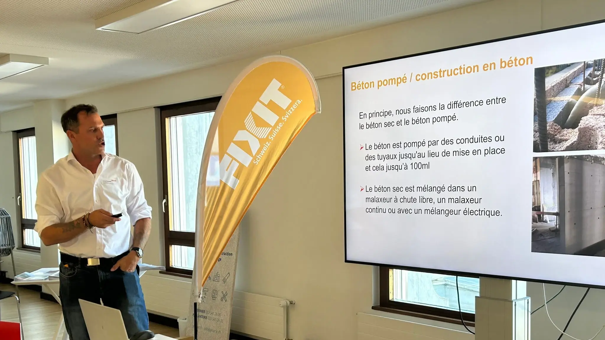 Ein Fixit Mitarbeiter stellt vor einer Fixit Beach Flag die Folie zum Thema Pumpbeton vor