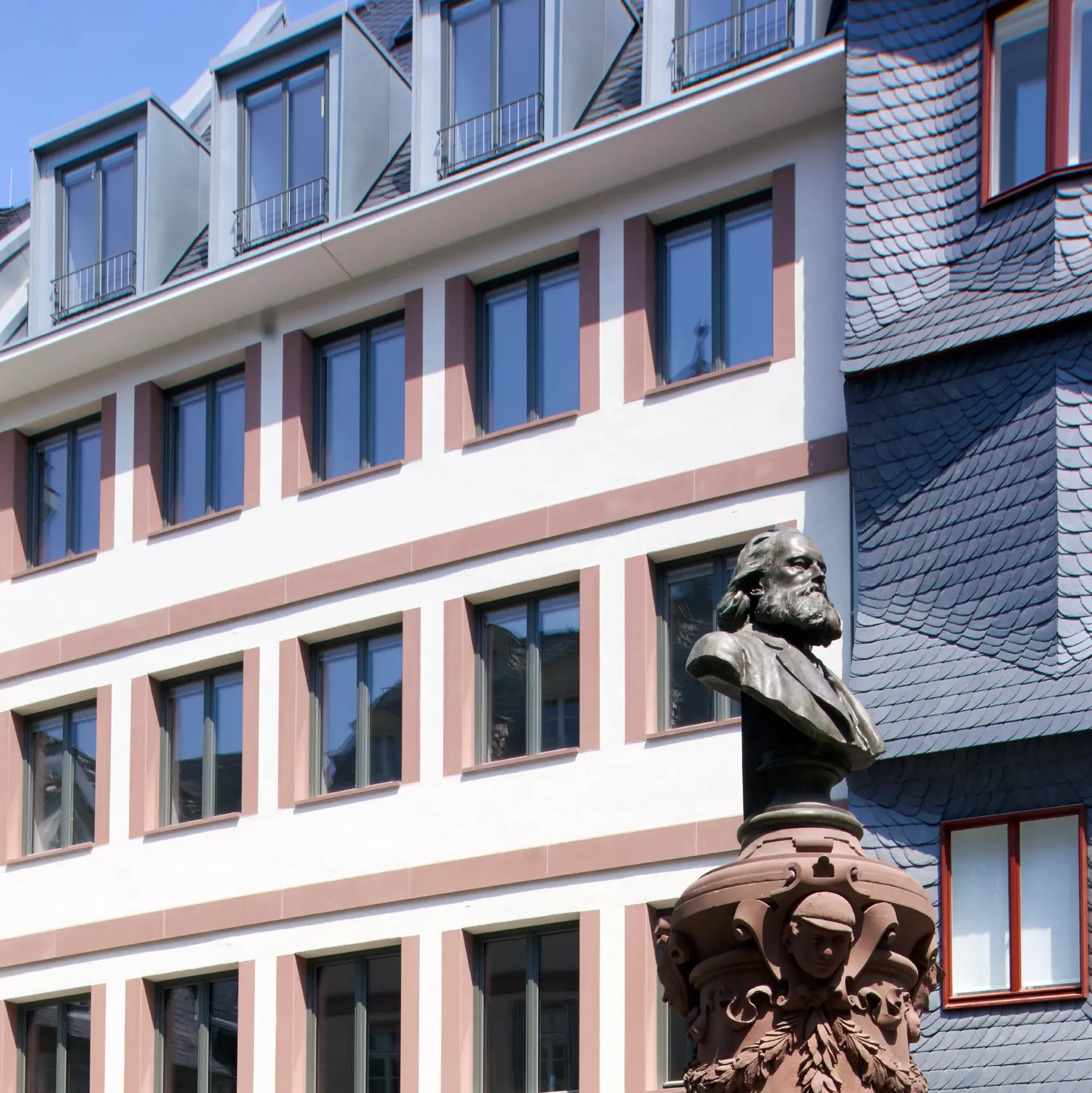 Perspektive auf die Seite des renovierten Objekts in Frankfurt mit einer Statue im Vordergrund