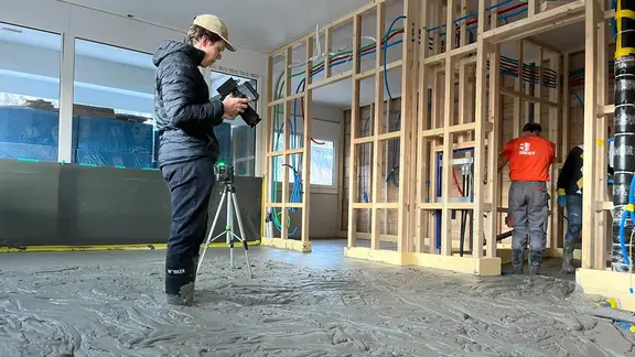 Dennis Brunner steht mit Gummistiefeln im Fixit POR Schaummörtel und filmt Detailaufnahmen mit der Videokamera