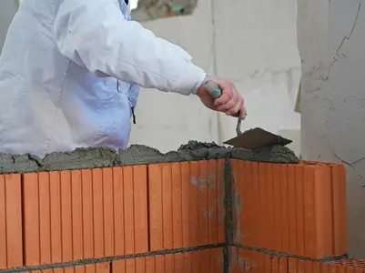 Arbeiter bei der Verarbeitung von Mauermörtel an einer Ziegelwand