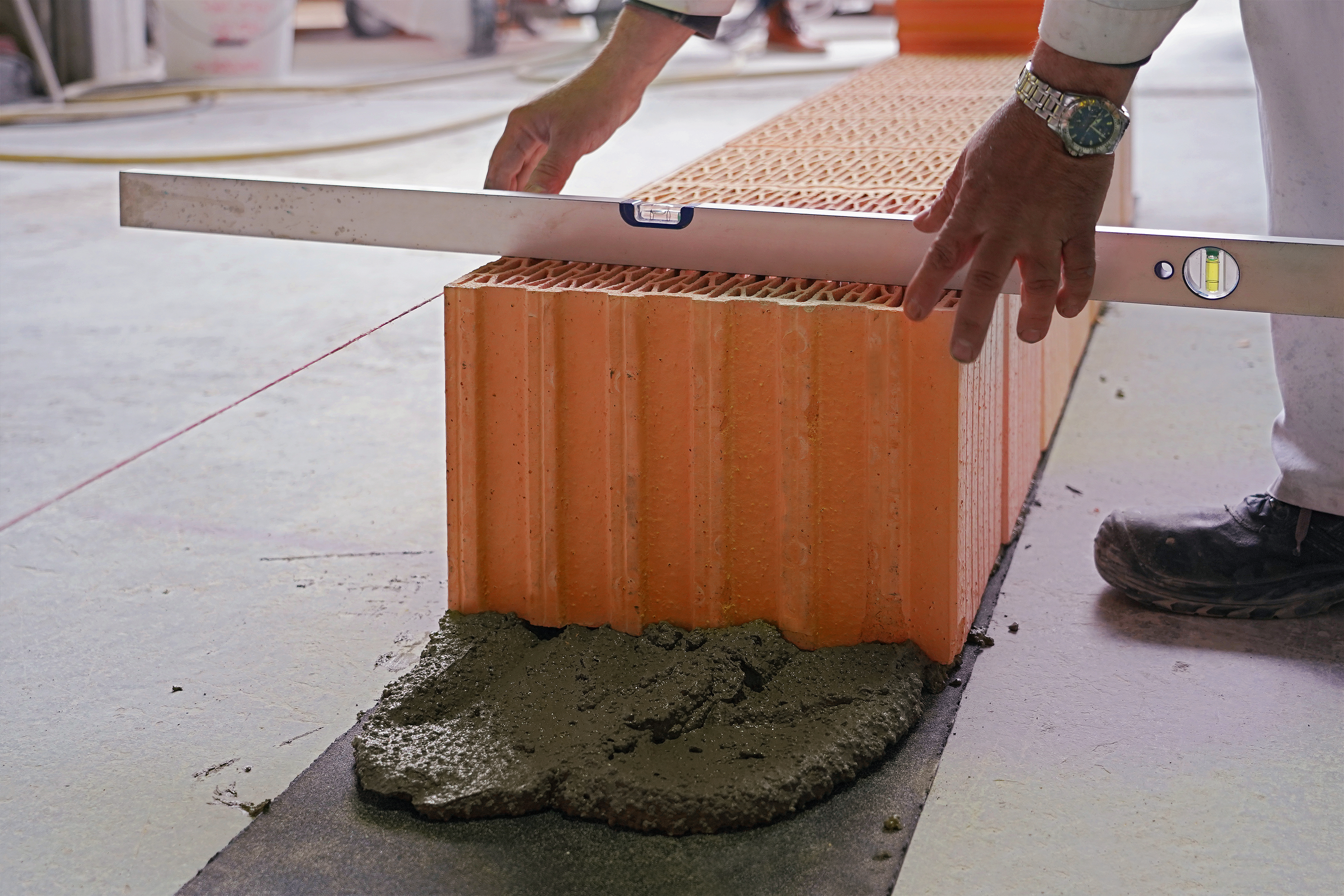 Die Ausrichtung der Steinreihe wird mit Hilfe einer Wasserwaage überprüft