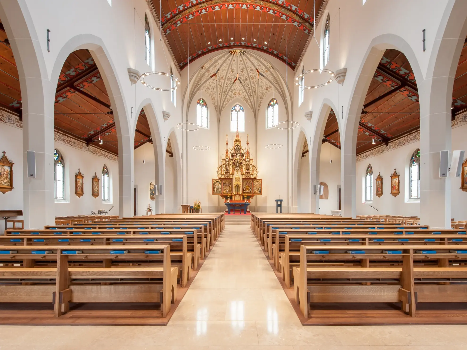 Intérieur d'une nef avec des arcs brisés blancs et un plafond en bois décoré