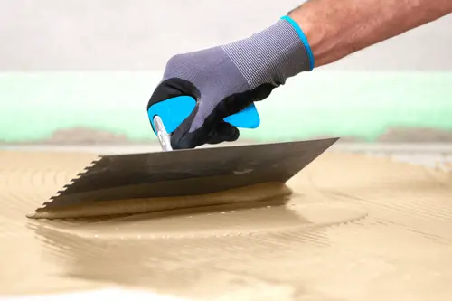 Hand mit Spachtel verteilt Grundierung 
