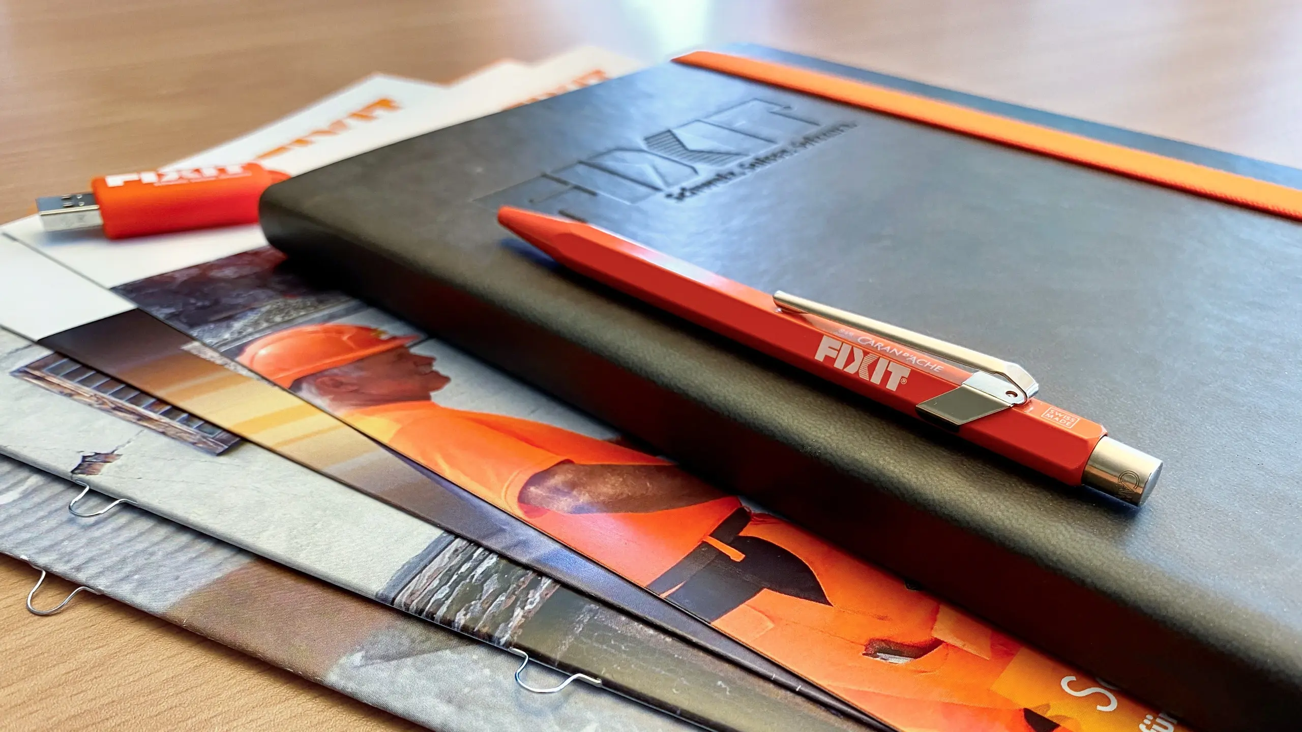 Opuscoli e un taccuino grigio scuro con penna arancione