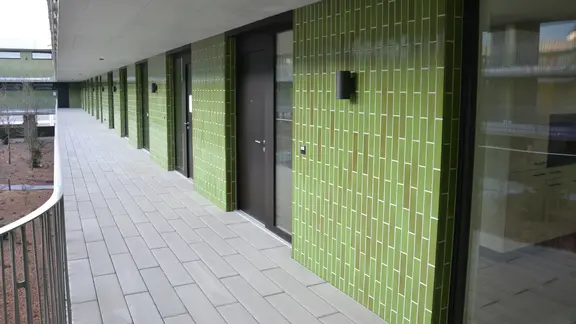 Détail de l'entrée d'un immeuble d'habitation avec des carreaux verts sur l'ITE grâce à Fixit StoneEtics®.