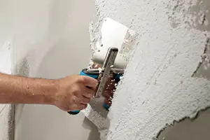 Hand mit Kelle verputzt eine Wand 