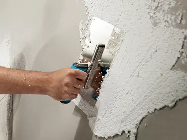 Hand mit Kelle verputzt eine Wand