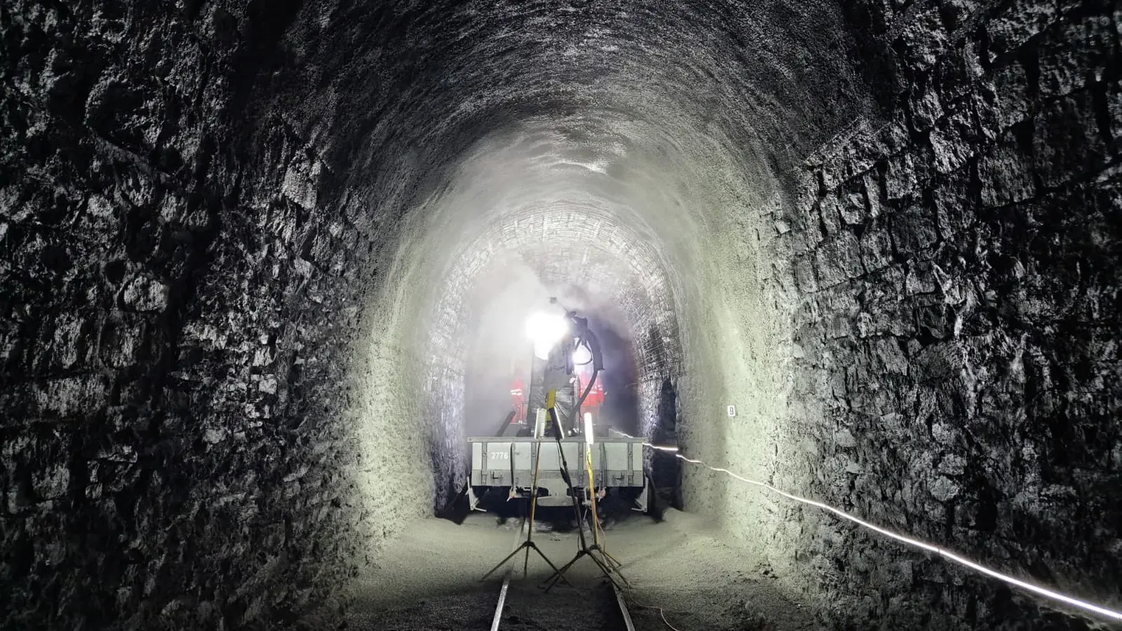 Innerhalb des Scheiteltunnels bei Muttbach-Belvédère stehen zwei Scheinwerfer und man sieht das Fahrzeug für die Tunnelsanierung