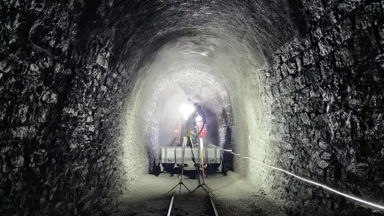 Innerhalb des Scheiteltunnels bei Muttbach-Belvédère stehen zwei Scheinwerfer und man sieht das Fahrzeug für die Tunnelsanierung
