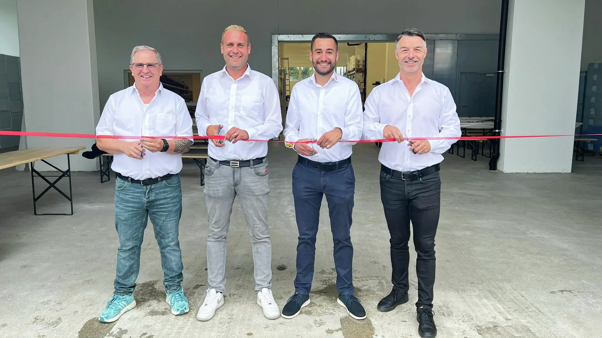 Andreas Ulrich, Marco Kern, Ralph Hermann und Walter Eigenmann stehen von links nach rechts aufgereiht jeweils mit einer Schere vor einem roten Band zur Eröffnung des Lagerstandorts Wilen