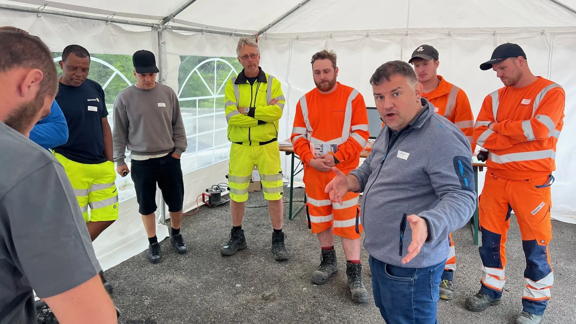 Remo Schwendener steht als Vortragender inmitten der Schulungsgruppe in einem weissen Pavillion