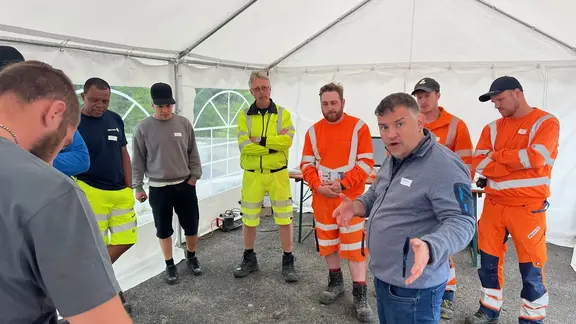 Remo Schwendener steht als Vortragender inmitten der Schulungsgruppe in einem weissen Pavillion