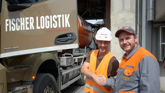 Un collaborateur de Fixit Logistik serre la main d'un client de Fischer Logistik devant le camion
