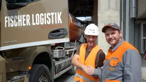 Un employé de Fixit serre la main d'un chauffeur de camion de Fischer Logistik devant son camion