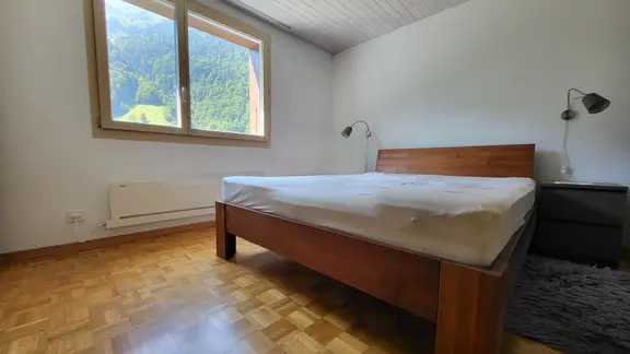Schlafzimmer mit Stäbchenparkett, grossem Holzbett und mit Fixit 252 sanierten Innenwänden in weiss