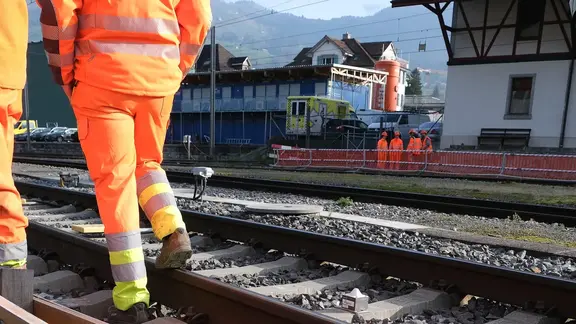 Gleisbereich am Bahnhof Schwyz mit Bauarbeitern im Vordergrund und Fixit POR Schaumbeton Silo im Hintergrund für die Leitungsverfüllung einer 50 Meter langen, unterirdischen Leitung