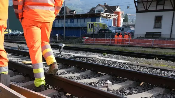 Gleisbereich am Bahnhof Schwyz mit Bauarbeitern und Fixit POR Silo im Hintergrund