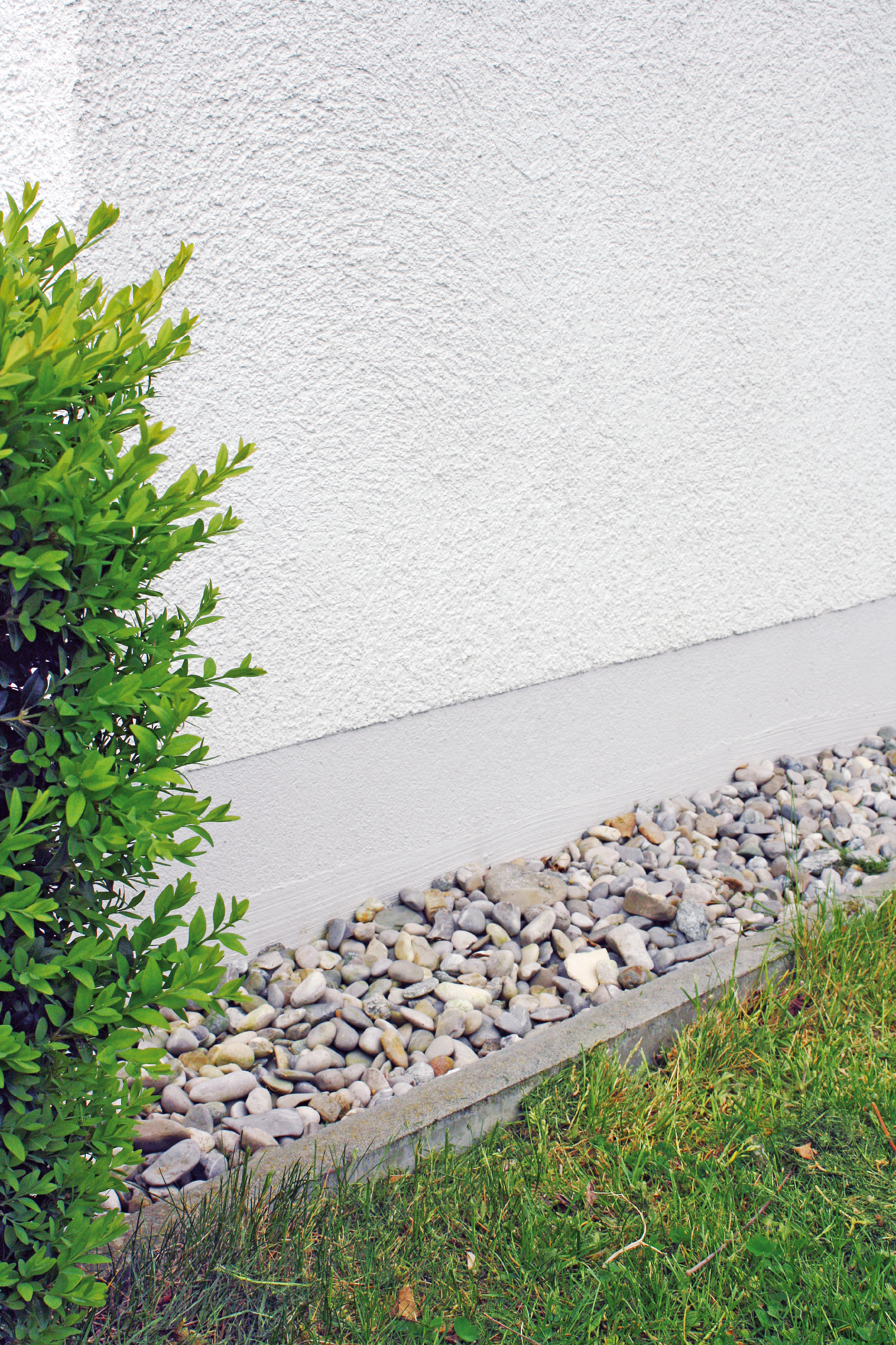  Der Sockelbereich einer Außenfassade, sorgfältig verputzt und verstärkt, bietet Schutz vor Feuchtigkeit und Beschädigungen.