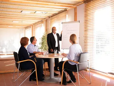 One person presents and three other people at the table listen attentively