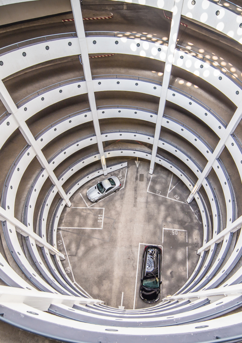 Eine kreisförmige Tiefgaragenauffahrt von oben mit parkenden Autos