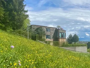 Außenansicht eines Hauses, umgeben von einer grünen Landschaft im Vordergrund.