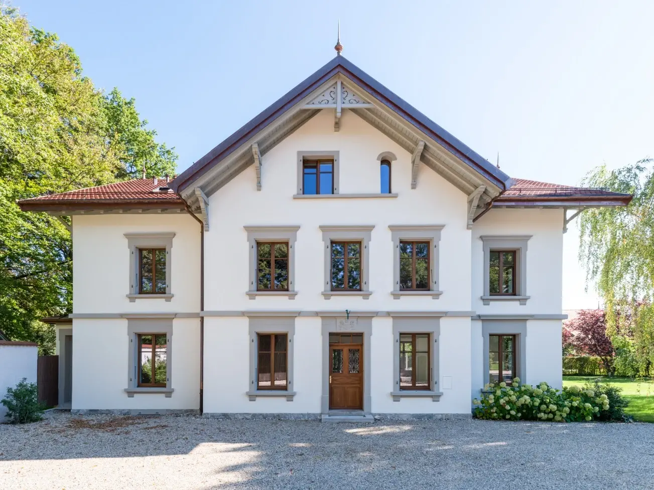 Gesamtes Gebäude mit Eingangstüre und Fenstern sowie dem Vorplatz