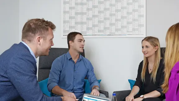 Vier Personen sitzen am Tisch und führen eine Diskussion