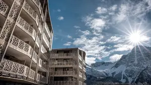 Hotel in den Bergen bei Sonnenschein im Winter mit Bergpanorama und Schnee im Hintergrund