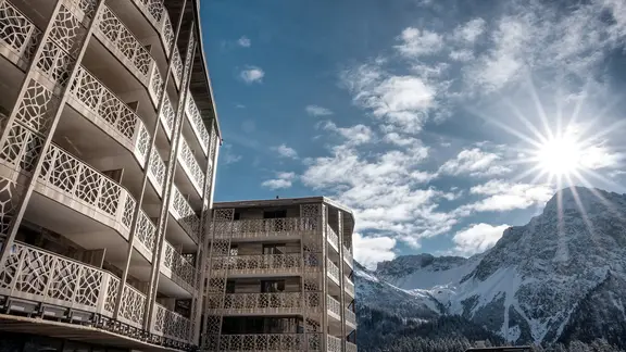 Hôtel à la montagne par temps ensoleillé en hiver avec un panorama de montagnes et de la neige en arrière-plan