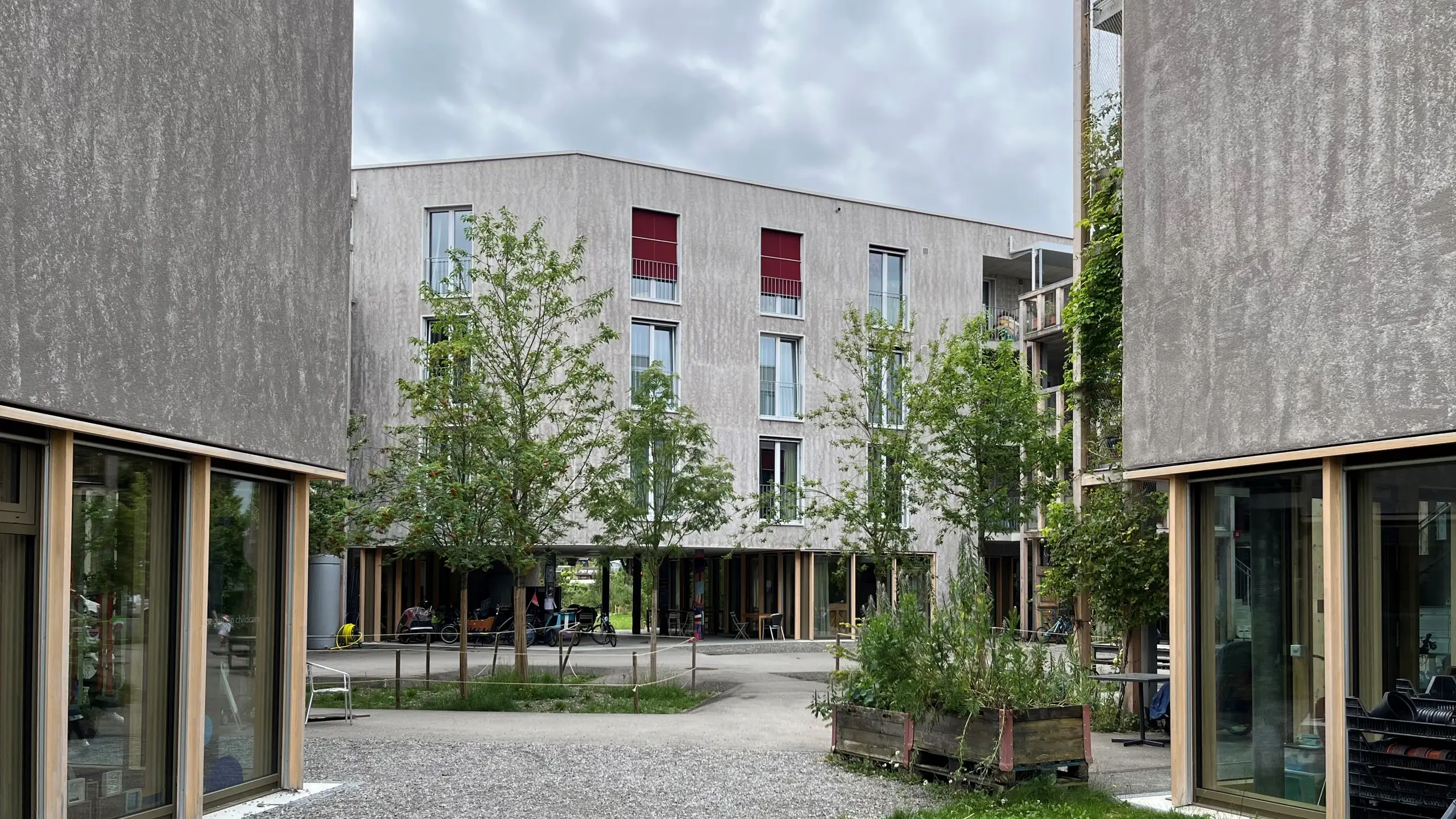 A gauche et à droite, façade bicolore avec les produits Fixit et au centre, en arrière-plan, un bâtiment complet de la coopérative Huebergass.