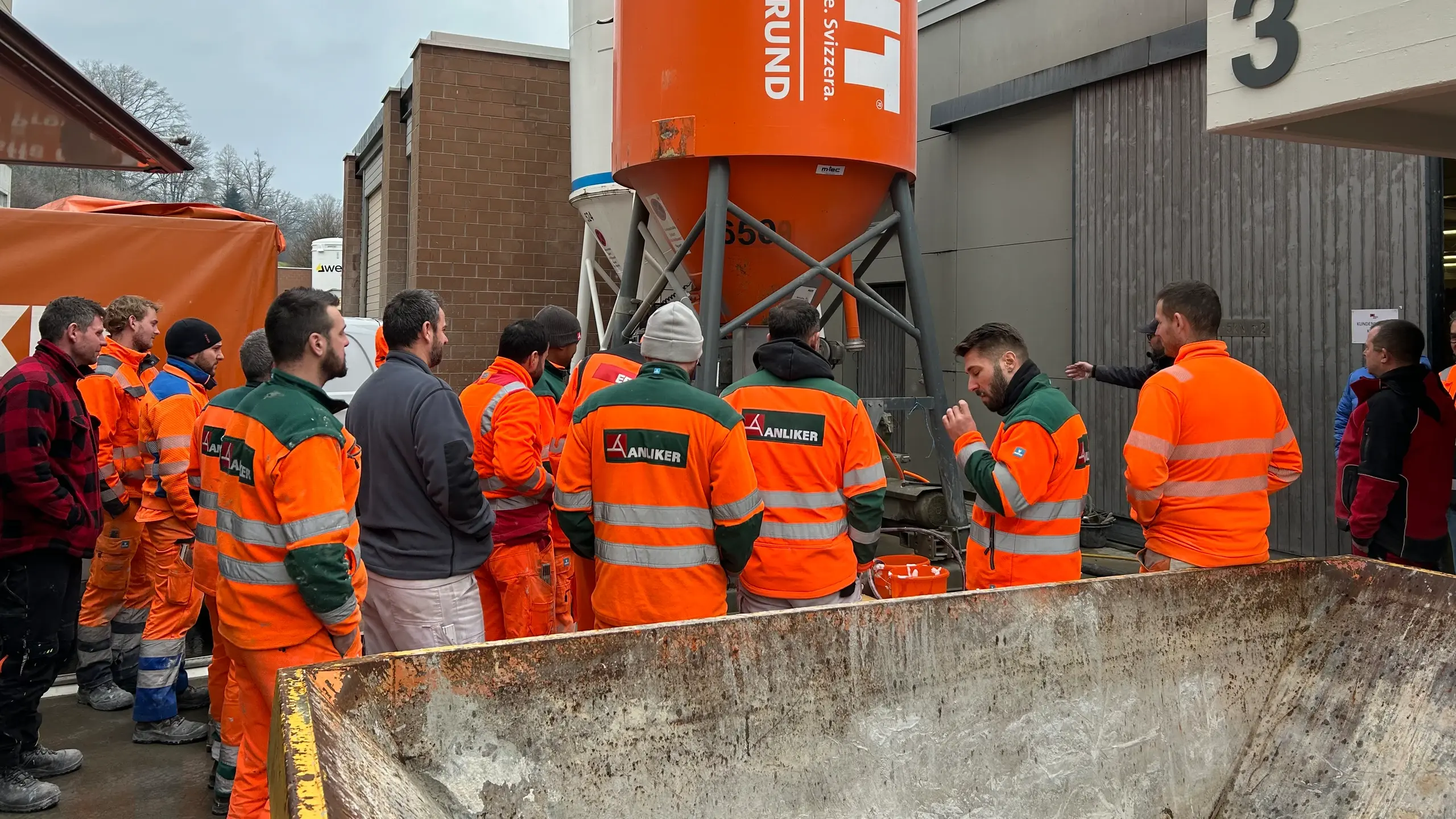 Un groupe en tenue de sécurité orange est rassemblé autour du silo Fixit POR.