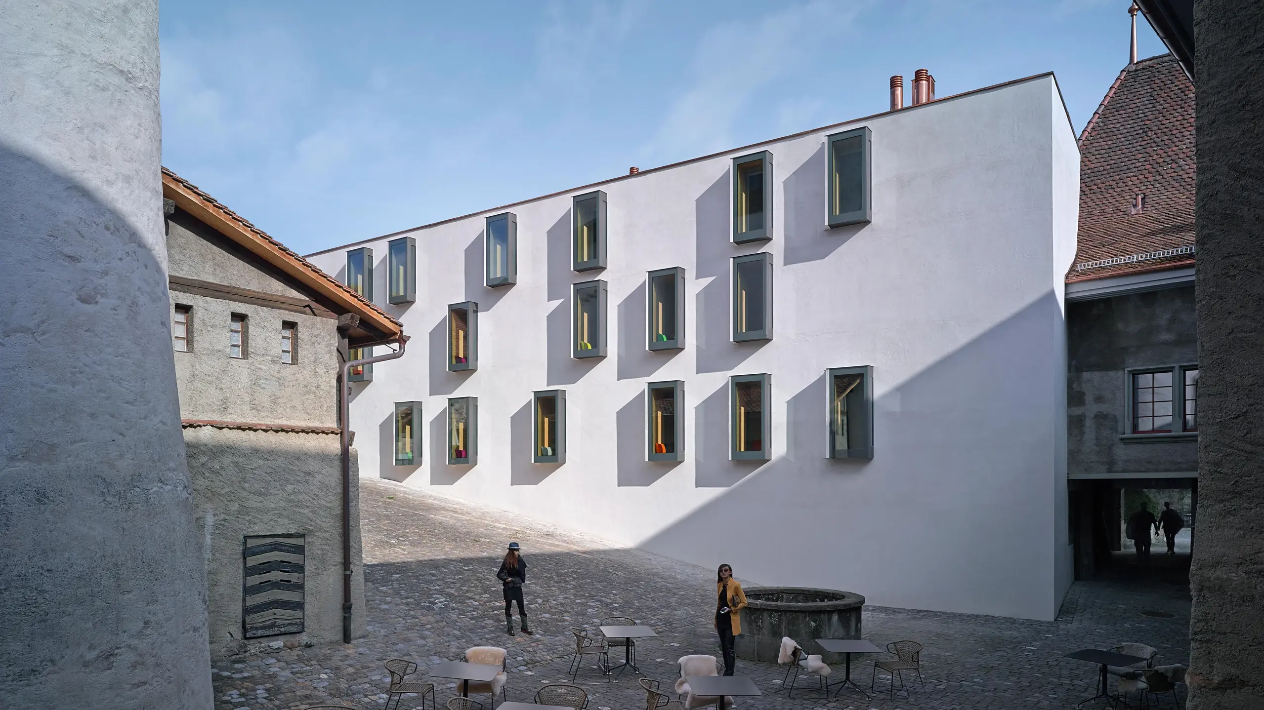 Modern, white façade of a historic prison with cubic bay windows