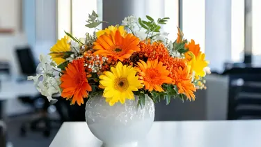 Gemischter Blumenstrauss ohne Rosen mit orangen, gelben und weissen Blüten in einer weissen Keramikvase