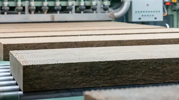 Zugeschnittene Steinwolle-Dämmplatten laufen über ein Rollband in der Flumroc Produktionshalle
