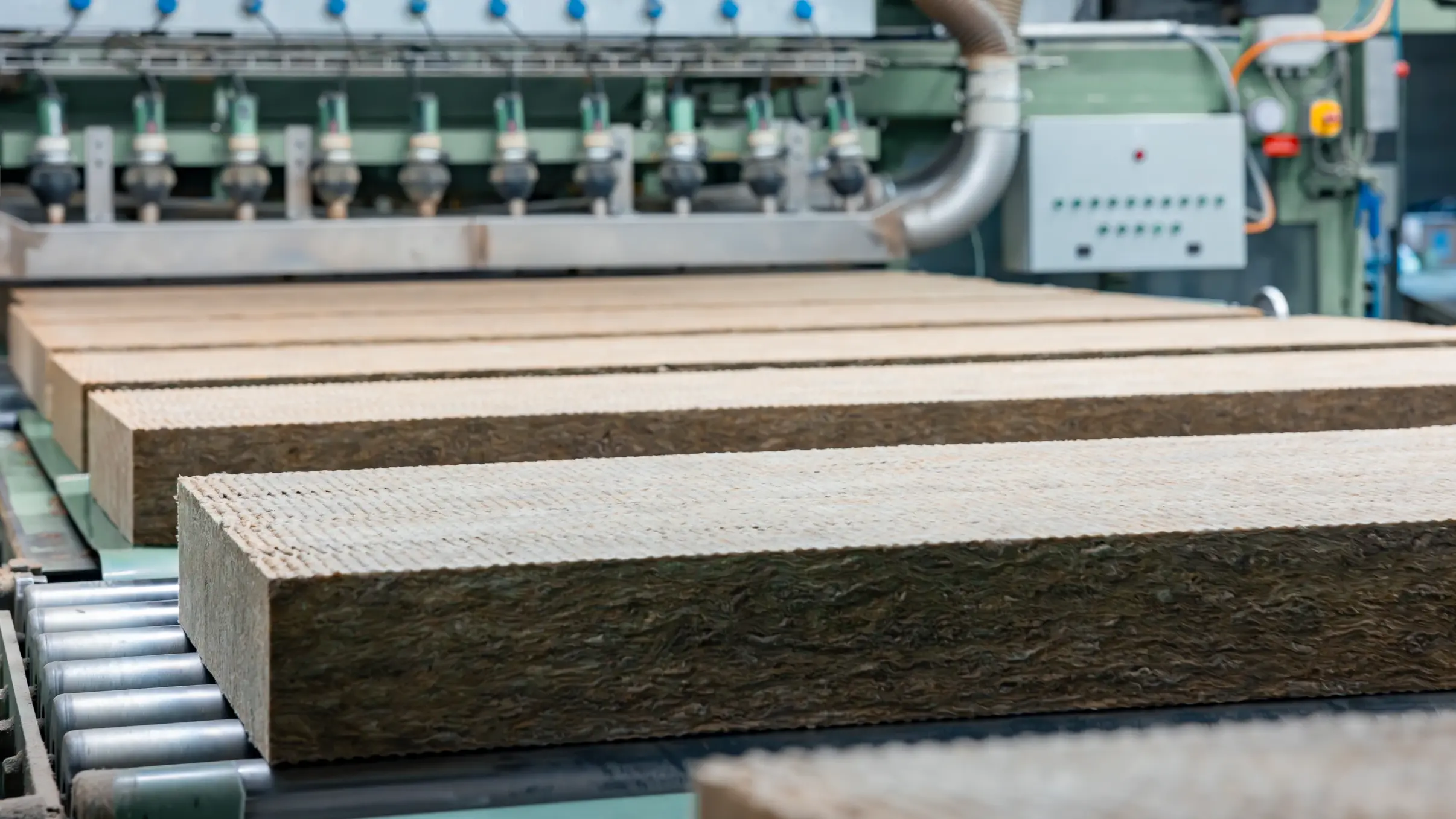 Zugeschnittene Steinwolle-Dämmplatten laufen über ein Rollband in der Flumroc Produktionshalle