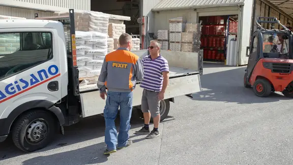 Fixit Mitarbeiter aus dem Logistikteam übergibt mehrere Paletten mit Ware an einen Kunden von Gisano