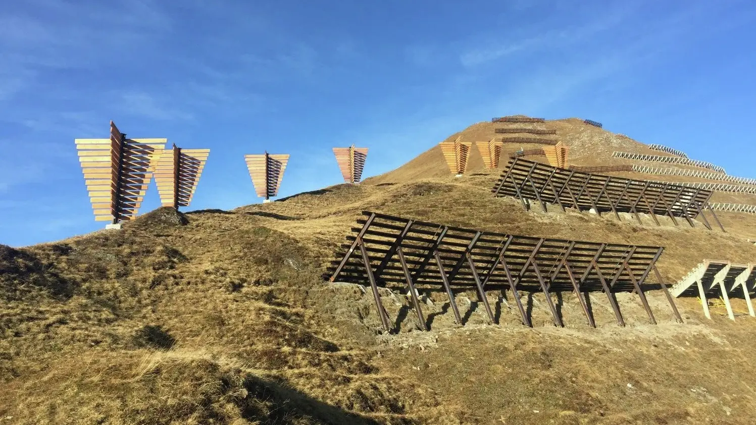 Chüenihorn mit getrockneter Wiese, Holzstrukturen und der Lawinenverbauung in Gipfelnähe