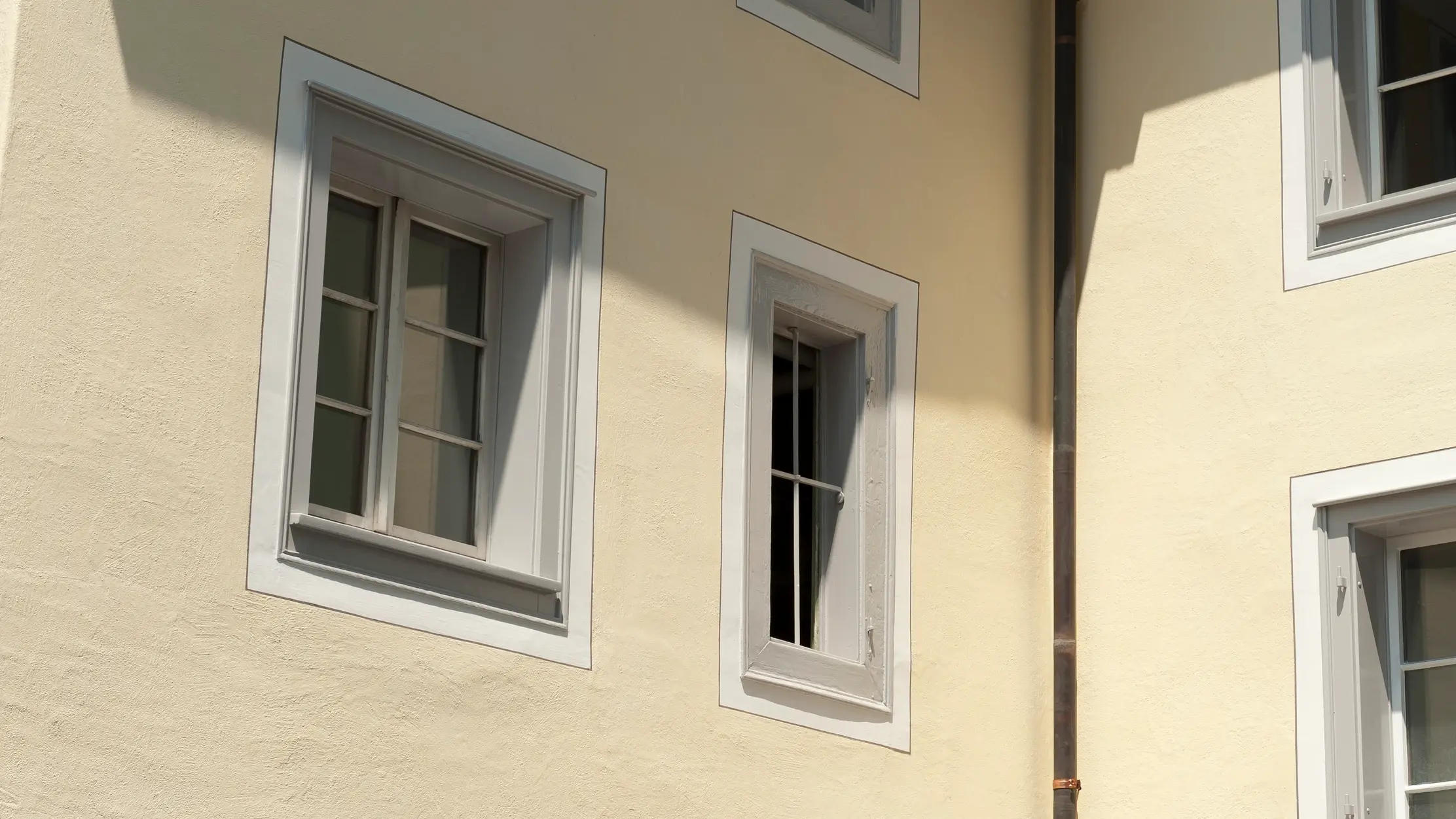 Vue détaillée d'une façade historique jaune clair avec des fenêtres à croisillons encadrées