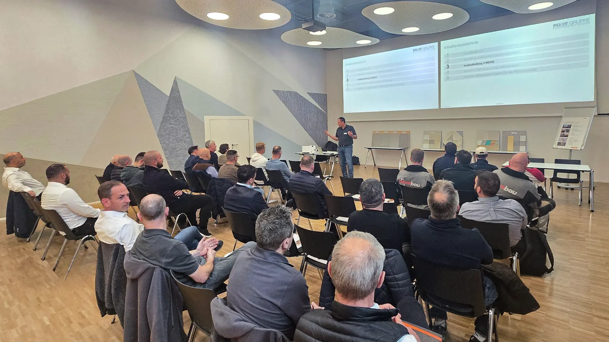 Ansicht auf alle Teilnehmenden, die in Reihen vor der Präsentation von Ralf Bannwitz sitzen